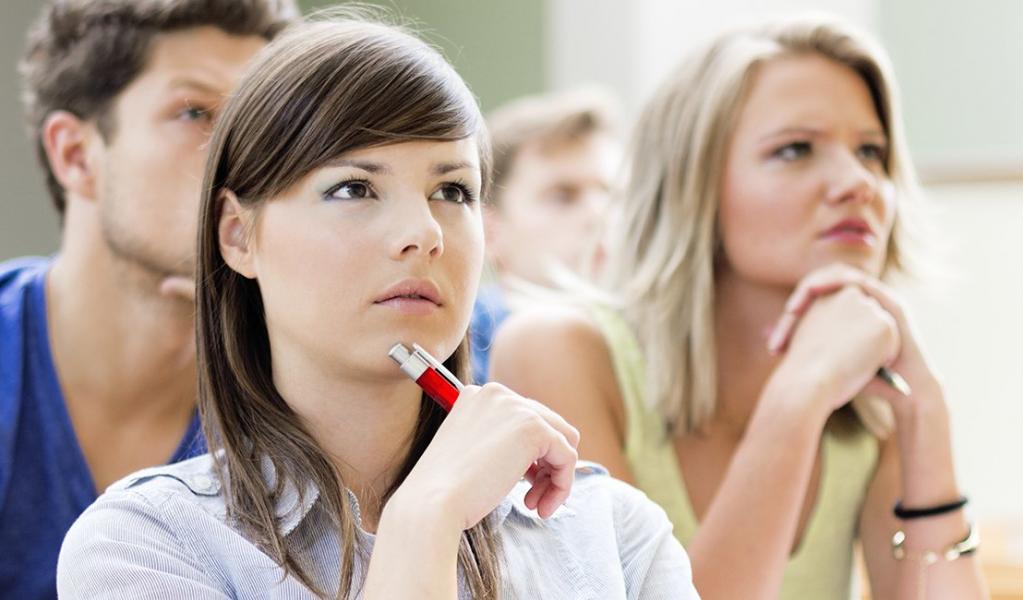 young woman sits in a lecture hall, looking forward